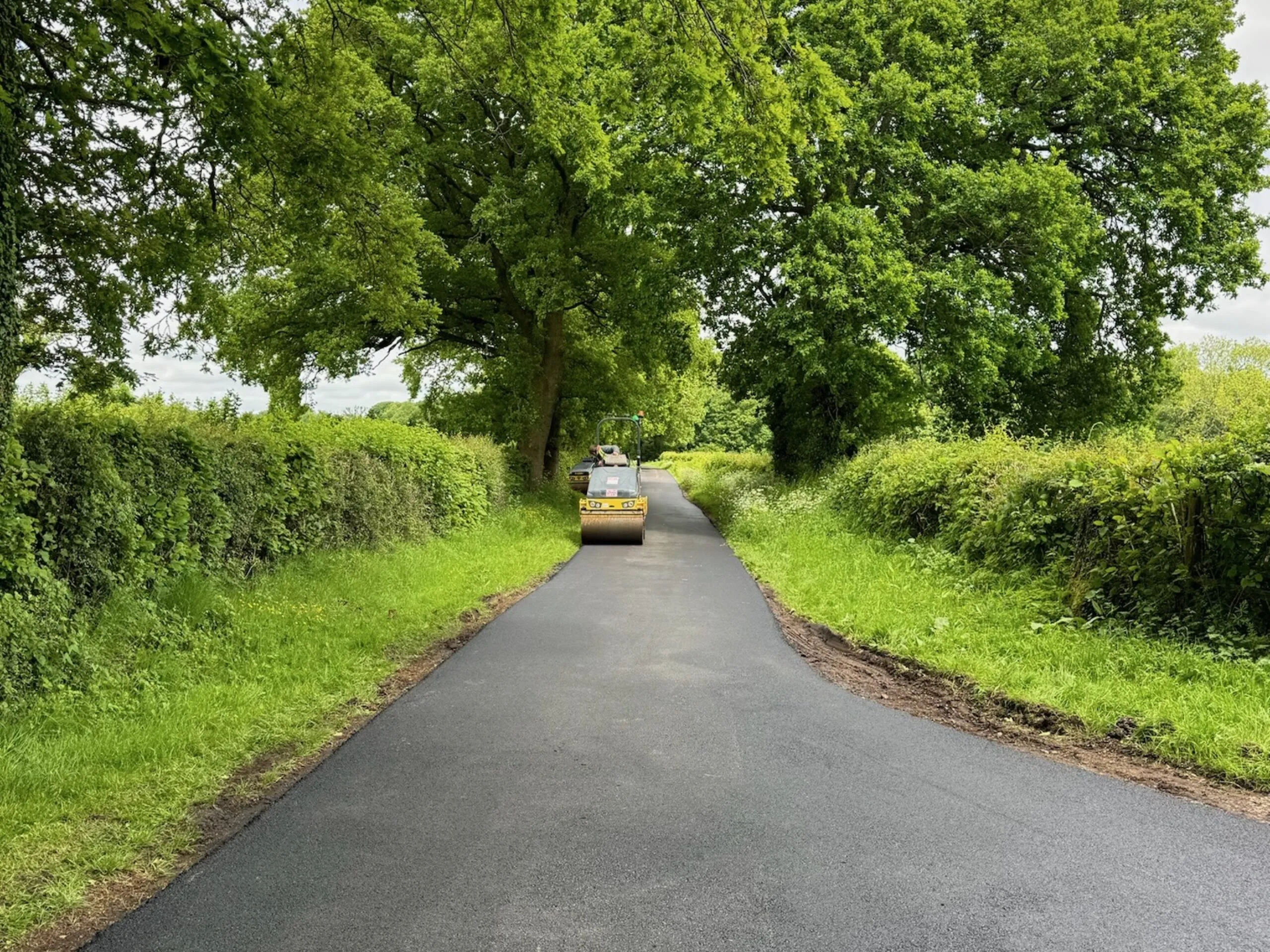 A tarmaced private road being installed with a roller