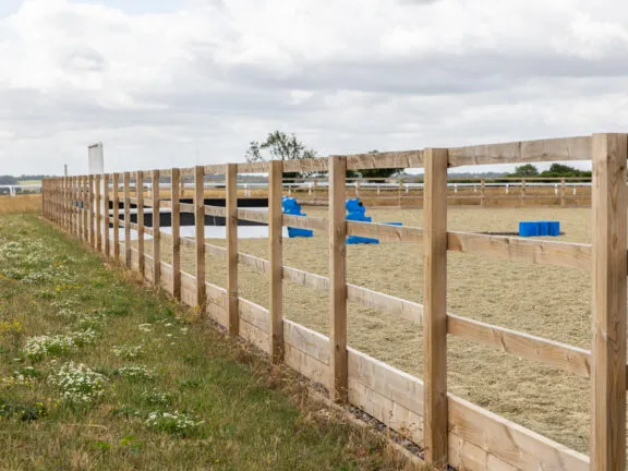 Post and rail fencing alongside a sand and fibre arena