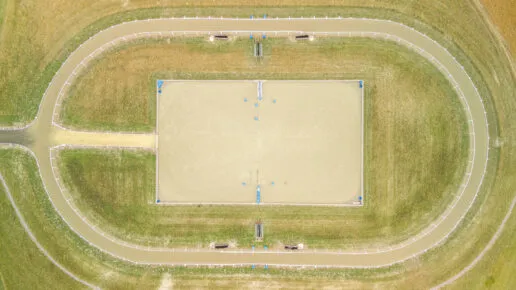Aerial view of an oval all-weather gallop track with a sand arena in the centre