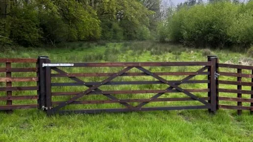 A single gateway in a post and rail fence within a field