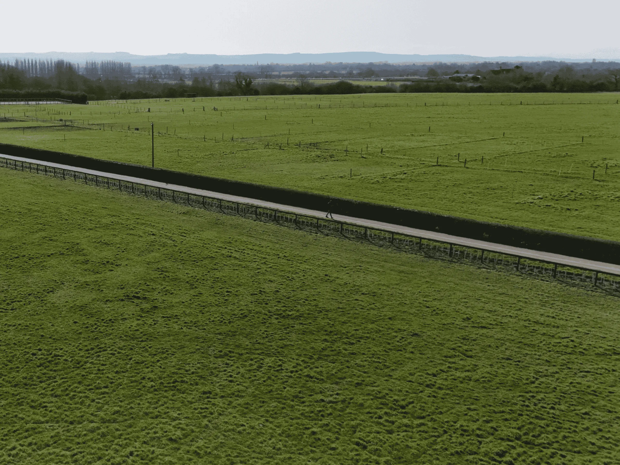 An aerial shot of a line of Horse Net and Post and Rail fencing between a horse paddock and a driveway
